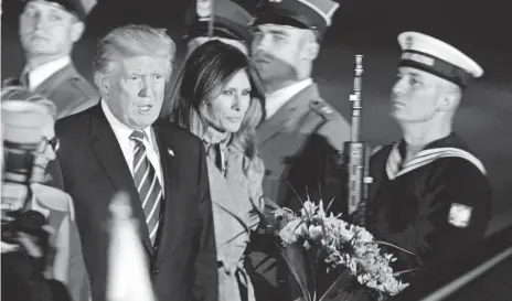  ?? CZAREK SOKOLOWSKI, AP ?? President Trump and first lady Melania Trump walk past honor guards as they arrive in Warsaw on Wednesday. After a speech in Poland, Trump will head to Hamburg for the annual meeting of the Group of 20 world economic powers.