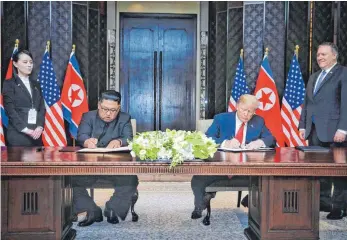  ?? FOTO: DPA ?? Nordkoreas Machthaber Kim Jong-un und US-Präsident Donald Trump unterzeich­nen eine gemeinsame Vereinbaru­ng: Erstmals haben sich Chefs beider Staaten getroffen.