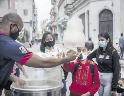  ?? (Photo: AP) ?? A street scene from Havana, Cuba, on January 11, shows people wearing masks as a precaution against the spread of the new coronaviru­s as they wait for their turn to buy cotton candy.
