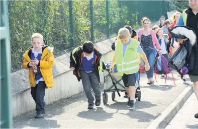  ??  ?? Pavement pounders Pupils from both schools are joined by parents on the route