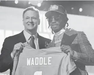  ?? TONY DEJAK/AP ?? Alabama wide receiver Jaylen Waddle, right, holds a team jersey with NFL Commission­er Roger Goodell after being chosen by the Dolphins with the sixth pick in the draft Thursday in Cleveland.