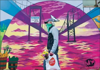  ?? PHOTOS BY CHRIS RILEY — TIMES-HERALD ?? A man wears a bandanna over his face as he carries flowers from the Farme’s Market in downtown Vallejo. The market returned after Gov. Gavin Newsome deemed it an essential business.