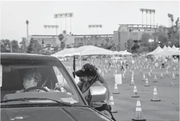  ?? PHILIP CHEUNG/THE NEW YORK TIMES ?? Maria Rivera gets a COVID-19 vaccine injection Thursday at Dodger Stadium. Los Angeles County officials say the call for testing has collapsed. Not long ago, the county was conducting over 350,000 tests weekly.