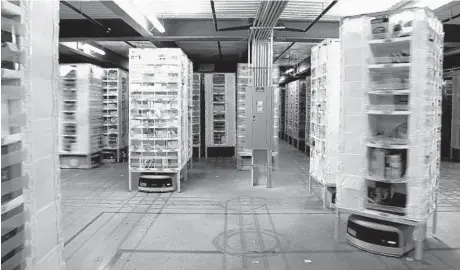  ?? BARBARA HADDOCK TAYLOR/BALTIMORE SUN ?? Carts that store a variety of items are moved by robot power at Amazon’s 1 million-square-foot warehouse on Broening Highway. The robots deliver products to work stations, saving employees the time it would take to walk the warehouse floor and search...