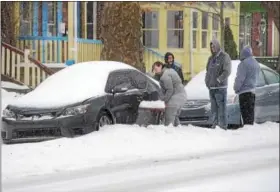  ?? TOM KELLY III — FOR DIGITAL FIRST MEDIA ?? Three guys watch as Brooke Kissinger shovels out her car on High Street near Price Street in Pottstown during Tuesday’s snow storm. In defense of the guys, Brooke says she likes to shovel snow and besides the guys were out earlier shoveling and they...