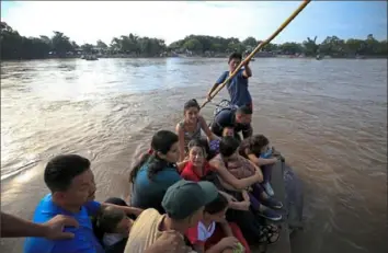  ?? Rebecca Blackwell/Associated Press ?? More than a dozen Honduran migrants ride a raft Friday across the Suchiate River between Guatemala and Mexico.