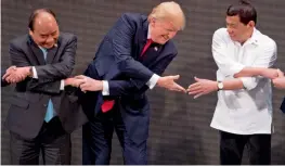  ?? — AP ?? US President Donald Trump, center, reacts as he does the ‘ Asean- way handshake’ with Vietnamese Prime Minister Nguyen Xuan Phuc, left, and Philippine President Rodrigo Duterte on stage during the opening ceremony at the Asean Summit at the Cultural...