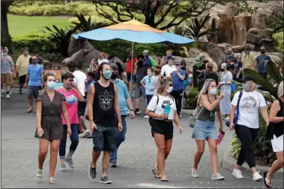  ?? The Associated Press ?? SEAWORLD: Guests wearing masks stroll through SeaWorld as it reopened with new safety measures in place Thursday in Orlando, Fla. The park had been closed since mid-March to stop the spread of the new coronaviru­s.