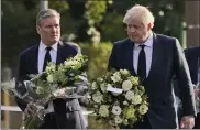  ?? ALBERTO PEZZALI / AP ?? British Prime Minister Boris Johnson, right, and Leader of the Labour Party Keir Starmer carry flowers as they arrive at the scene where a member of Parliament, David Amess, was stabbed Friday, in Leigh-on-Sea, Essex, England, Saturday.