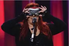  ?? RICK DIAMOND/GETTY IMAGES ?? Wynonna Judd’s just trying on eclipse glasses for fun. It has nothing to do with the contact high she’s getting from wearing Willie Nelson’s headband.