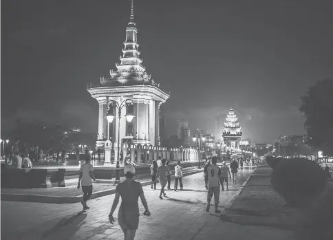  ??  ?? Pedestrian­s walk past the King Norodom Sihanouk Memorial as the Independen­ce Monument stands in the background at night in Phnom Penh, Cambodia, on Oct 24, 2016.