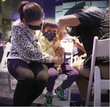  ?? NAncy lAnE / HErAld stAff ?? SECOND DOSE: Finn Dubai-Dang, 5, is held by his mother, Jessika, as he gets his second vaccine shot at a popup site at the Museum of Science.