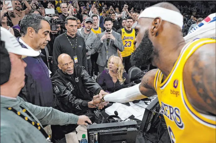  ?? Ashley Landis The Associated Press ?? Lakers forward Lebron James, right, shakes hands with Kareem Abdul-jabbar after he broke the former Lakers center’s all-time scoring record Tuesday night.