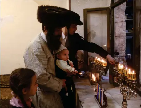  ?? (Marc Israel Sellem) ?? LIGHTING HANUKKAH candles in Jerusalem’s Mea She’arim neighborho­od. Both religious and secular can unite around the joy of the holiday.