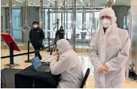  ??  ?? security guards wear hazmat suits check the temperatur­e of customers at a shopping mall in Beijing on thursday.