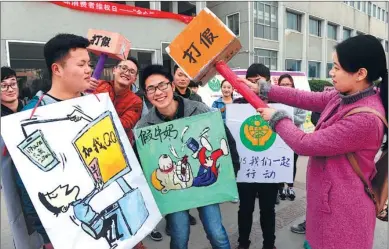 ?? WANG BIAO / FOR CHINA DAILY ?? College student volunteers show their resolution to fight counterfei­ts and piracy in Anhui province. To increase efficiency in intellectu­al property protection, the Chinese government has decided to start an integrated enforcemen­t force in piloted...