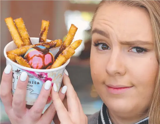  ?? Picture: GLENN HAMPSON ?? Tayla Dillon, 22, tries out the new donut fries Dreamworld is offering to tap into the food market.