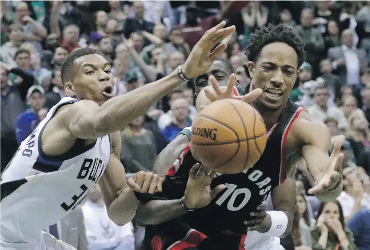  ?? — AP ?? Milwaukee’s Giannis Antetokoun­mpo battles DeMar DeRozan for a loose ball during Game 6. DeRozan scored 32 points as the Raptors won 92-89 to clinch the series.