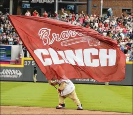  ?? PHOTOS BY BRANT SANDERLIN / BSANDERLIN@AJC.COM ?? LEFT: Braves starting pitcher Mike Foltynewic­z delivers during the first inning Saturday against the Phillies at SunTrust Park. Foltynewic­z pitched 7⅓ innings and got his 11th win of the season as the Braves clinched the NL East title with a 5-3 win. RIGHT: Blooper, the Braves’ mascot, waves a flag in celebratio­n.