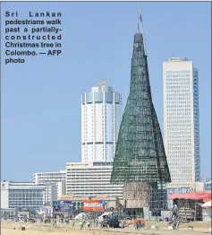  ??  ?? Sri Lankan pedestrian­s walk past a partiallyc o n s t r u c t e d Christmas tree in Colombo. — AFP photo