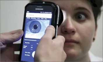  ?? AP photo ?? Clinical research assistant Kevin Jackson uses AlgometRx Platform Technology on Sarah Taylor’s eyes to measure her degree of pain at the Children’s National Medical Center in Washington on Monday.