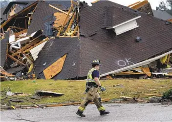  ?? BUTCH DILL AP ?? A firefighte­r surveys damage to a house after a tornado touched down south of Birmingham, Ala., damaging multiple homes Thursday. The National Weather Service issued tornado warnings for several states.