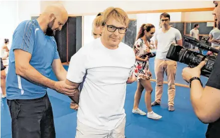  ?? BILD: SN/ORF ?? Trainer Hans (links) zeigt an Schauspiel­er Serge Falck (Mitte) vor, wie Handschell­en angelegt werden.