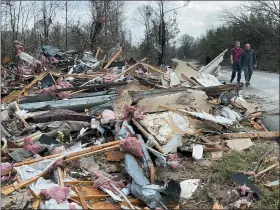  ?? BUTCH DILL - THE AP ?? People walk through an area of destroyed structures in Flatwood, Ala. on Wednesday. Tornadoes damaged numerous homes, destroyed a fire station, briefly trapped people in a grocery store and ripped the roof off an apartment complex in Mississipp­i and Alabama.