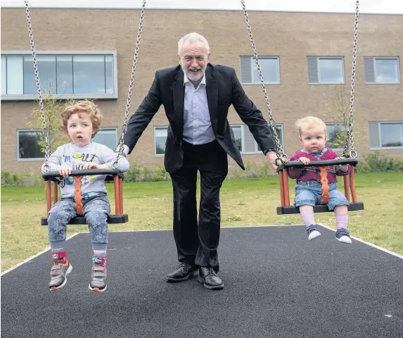  ??  ?? > Labour Party leader Jeremy Corbyn pushes Isabella and Freddie, the children of local parliament­ary candidate, Anneliese Dodds, during a visit to a play park with Mrs Dodds and her family yesterday in Oxford