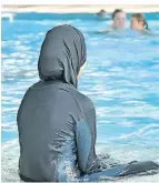  ?? FOTO: DPA ?? Eine muslimisch­e Schülerin sitzt in einem Burkini am Beckenrand.