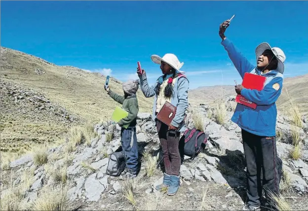  ?? CARLOS MAMANI / AFP ?? Alvaro, Roxana y Juan Carlos Cabrera buscando el pasado julio señal con el móvil en los Andes peruanos para recibir, debido a la pandemia, clases virtuales
