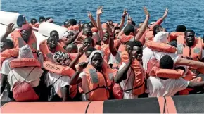  ?? AP ?? Migrants wave after being transferre­d from the NGO rescue ship Aquarius to Italian ships in the Mediterran­ean Sea yesterday. The migrants will be landed in Spain after Italy’s new populist government refused them safe port.