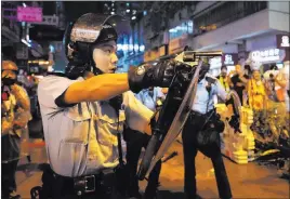  ?? Vincent Yu The Associated Press ?? A police officer draws a weapon at a pro-democracy protest Sunday in Hong Kong.