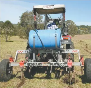  ??  ?? Back view of the rake with 200-litre drum and two pipes feeding the liquid soil conditione­r into the ripped soil.