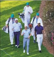  ?? Matt Slocum Associated Press ?? CADDIES at Augusta National, shown with golfers, from left, Fred Couples, Justin Thomas and Tiger Woods, have worn white coveralls for decades.