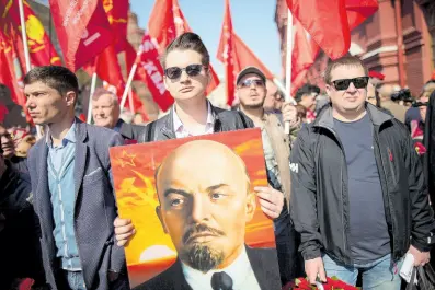  ?? AP ?? Communists and supporters walk with their flags and a portrait of Vladimir Lenin, the founder of the Soviet Union on April 22, 2019, to visit his mausoleum in Red Square in Moscow, Russia, to mark the 149th anniversar­y of his birth.