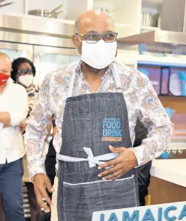  ?? ?? Tourism Minister Edmund Bartlett put on a branded apron for his cooking session with Chef Oji Jaja at the launch of the Jamaica Food and Drink Kitchen last Thursday.