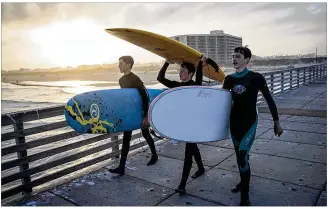  ?? PHOTOS BY NICK WAGNER / AMERICAN-STATESMAN ?? From left: Luke Merritt, 15, Liam Shannon, 14, and Paul Snow, 15, use a fishing pier earlier this month to walk out to deeper waters to surf in Port Aransas. Six months after Hurricane Harvey pummeled the city, 50 percent of the residents are not back...