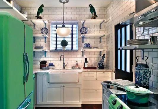  ??  ?? BEAUTIFULL­Y BALANCED. This view shows how the mint-green refrigerat­or and dishwasher with chrome trim, also from Elmira Stove Works, are a nice fit in this tiny kitchen. The white farmhouse-style sink, like the range, is surrounded by white subway tile...