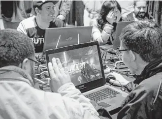  ?? Brett Coomer / Houston Chronicle ?? Houston Outlaws fans play Overwatch on a side table during the watch party for the esports team. The sport is looking to attract younger, tech-savvy consumers.