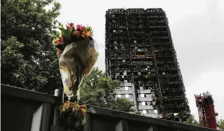  ?? Tolga Akmen - 15.jul.2017/Reuters ?? Flor é depositada próximo à Torre Grenfell, localizada no bairro de elite de Kensington e Chelsea, um mês após incêndio