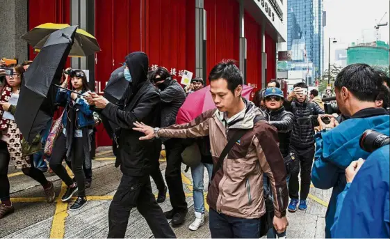  ??  ?? No pictures, please: Supporters using umbrellas to cover their faces as they leave the District Court in Hong Kong after three protesters were jailed for three years. — AFP