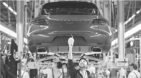  ?? — WP-Bloomberg photo ?? Employees work on the Porsche Macan sports utility vehicle assembly line inside the Porsche factory in Leipzig, Germany, on Dec 1, 2016.