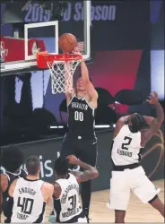  ?? KIM KLEMENT - THE ASSOCIATED PRESS ?? Brooklyn Nets forward Rodions Kurucs (00) dunks next to Los Angeles Clippers forward Kawhi Leonard (2) during the second half of an NBA basketball game Sunday, Aug. 9, 2020, in Lake Buena Vista, Fla.