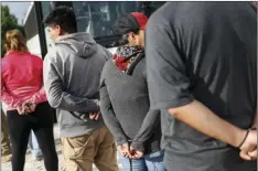  ?? PHOTO/JOHN ?? Suspects wait to be loaded onto a bus during an immigratio­n sting at Corso’s Flower and Garden Center on Tuesday in Castalia, Ohio. AP MINCHILLO