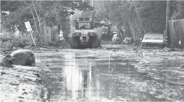  ??  ?? A car remains stuck in the mud as a cleanup crew work to clear mud beside a closed off section of US Hwy 101, flooded after mud and debris broke through an embankment along the freeway near the San Ysidro exit in Montecito, California. — AFP photos