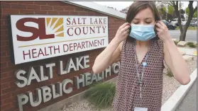  ??  ?? Health investigat­or Mackenzie Bray adjusts her mask at the Salt Lake County Health Department in Salt Lake City. Contact tracers around Utah’s capital have seen caseloads double and cooperatio­n wane since government leaders reopened the economy, Bray said.
(AP/Rick Bowmer)