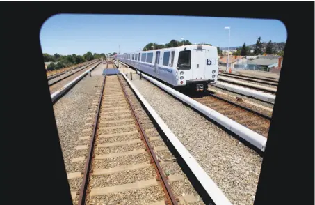  ?? Photos by Michael Macor / The Chronicle ?? A current BART train passes the window of a new train near South Hayward Station. The new fleet will cost BART $1.5 billion.