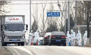  ?? — AP ?? Contagion: Workers disinfecti­ng passing vehicles due to the African swine flu outbreak on the outskirts of Beijing.