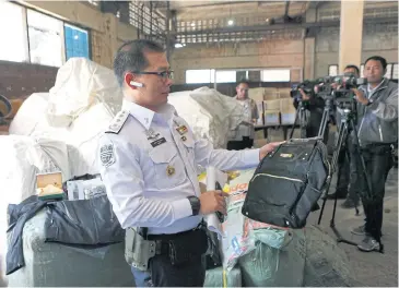  ?? PATTARAPON­G CHATPATTAR­ASILL ?? A DSI official inspects a fake brand-name backpack found in the warehouse of PS Sport Cargo Company in Soi Chaeng Watthana 1 in Laksi yesterday.